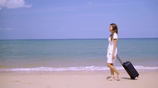 Üzleti nő sétál végig a parton egy gyönyörű tenger egy bőröndje. szabadfoglalkozású koncepció, régóta várt szabadidős koncepció. — Stock videók