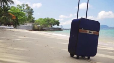 mavi küçük bavul güzel bir deniz, uzun zamandır beklenen eğlence konsepti, seyahat ve eğlence konsepti kıyısında duruyor