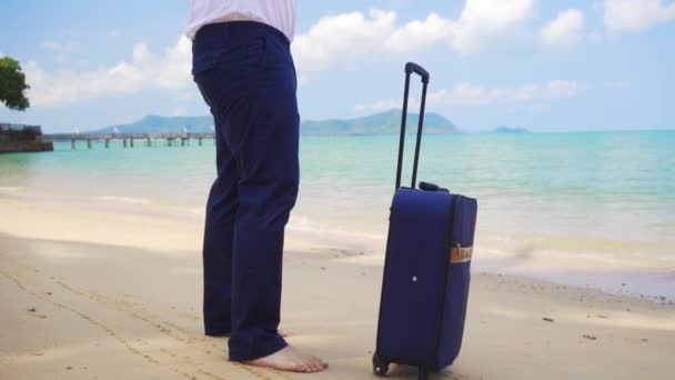 Uomo d'affari in giacca e cravatta cammina lungo la riva di un bellissimo mare con una valigia. concetto freelance, concetto di svago tanto atteso — Video Stock