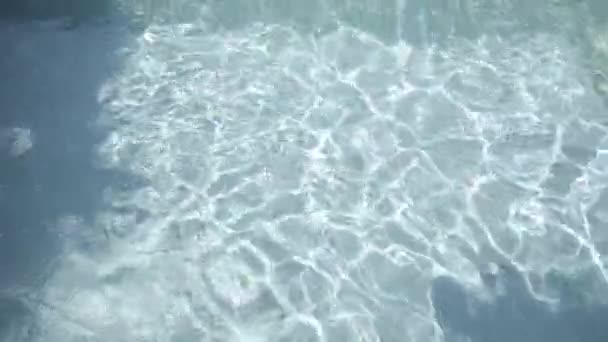 Agua azul claro en la piscina con reflejos de luz, el juego de la luz del sol. Movimiento lento — Vídeo de stock