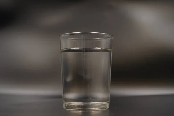 Sadece bir bardak su koyu ahşap bir masa üzerinde. Siyah bir zemin üzerine bir bardak maden suyu. Bir bardak su ile — Stok fotoğraf