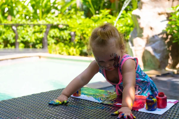 小さな女の子はプールの近くに指のペンキでペイント. — ストック写真