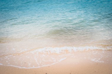Kumlu sahilde yumuşak bir mavi okyanus dalgası. Arkaplan