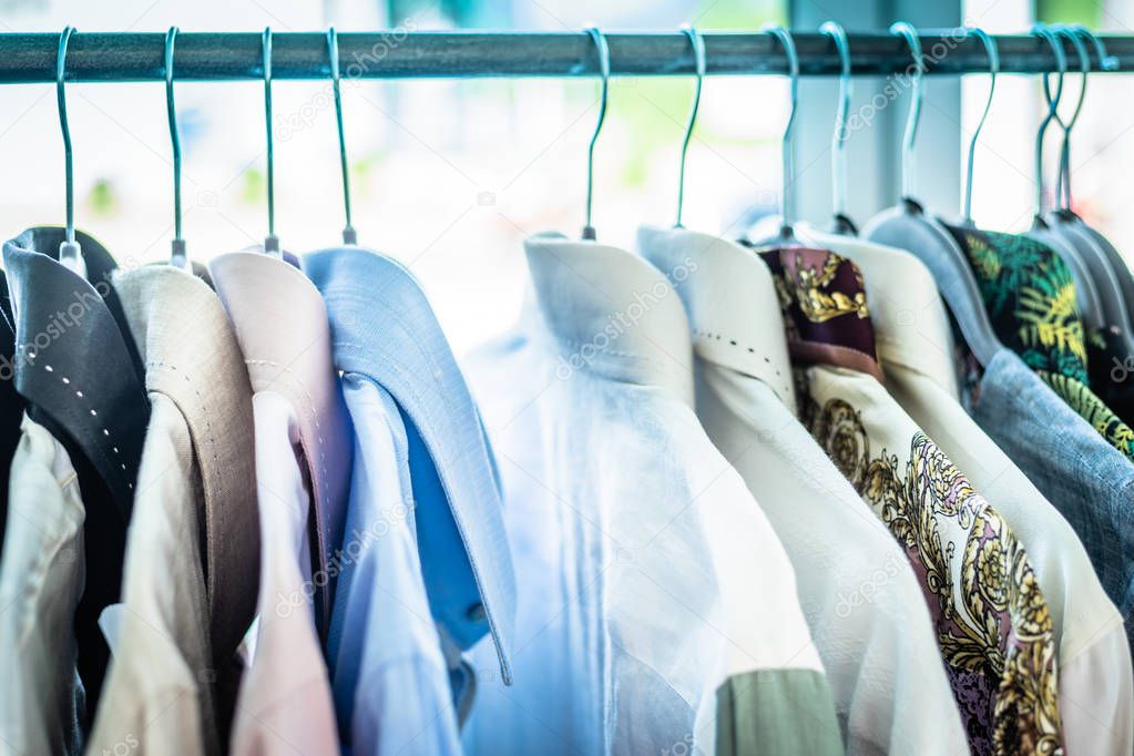 Summer wardrobe showcase. White and gray tone knitwear hanging on a coat rack. Selective focus, horizontal