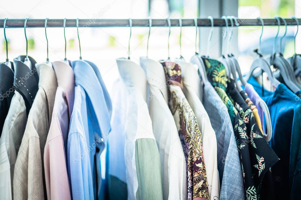 Summer wardrobe showcase. White and gray tone knitwear hanging on a coat rack. Selective focus, horizontal