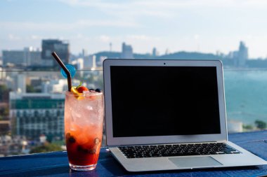 Ofis görüşüm. Dizüstü bilgisayar ve kokteyl dizüstü bilgisayarın yanında, arka planda plaj ile.