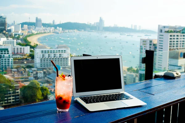 My office view. Laptop and cocktail next to the laptop, with the beach in the background.