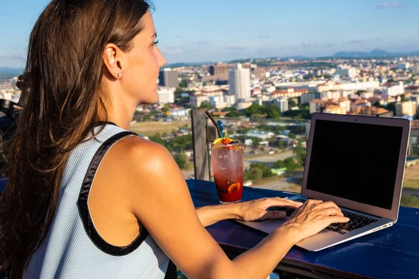 Lavori femminili su un computer portatile in un caffè sul tetto di un grattacielo con una bella vista panoramica della città, da vicino — Foto Stock