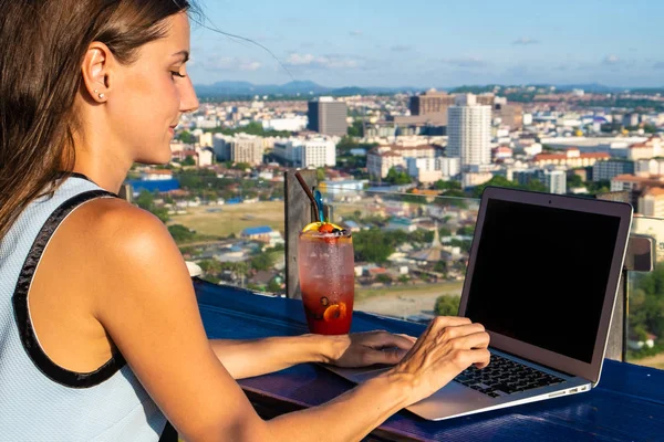 Lavori femminili su un computer portatile in un caffè sul tetto di un grattacielo con una bella vista panoramica della città, da vicino — Foto Stock