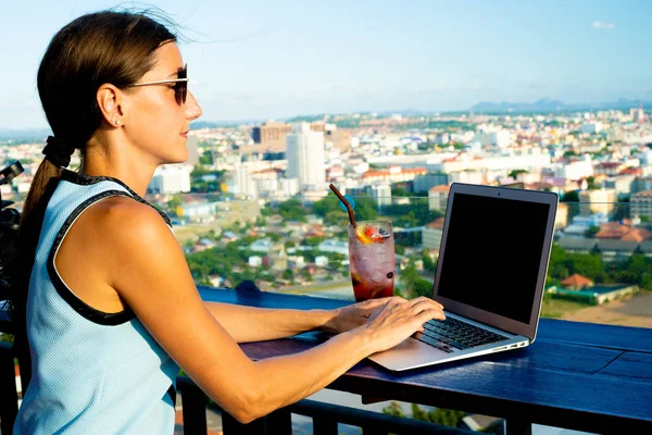 Lavori femminili su un computer portatile in un caffè sul tetto di un grattacielo con una bella vista panoramica della città, da vicino — Foto Stock