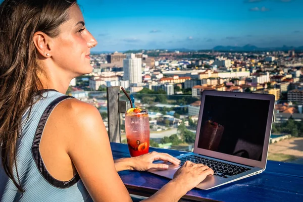 Lavori femminili su un computer portatile in un caffè sul tetto di un grattacielo con una bella vista panoramica della città, da vicino — Foto Stock