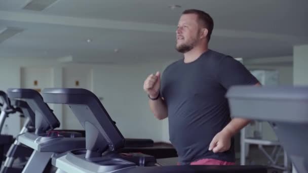 Full male runs on a treadmill in a gym. concept of weight loss and sport. side view — Stock Video