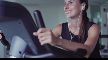 Kilo kaybı alarak kadının fitness salonunda egzersiz bisiklet kardiyo egzersiz. kadın kulaklıkla müzik dinler. Atlet oluşturucu kasları yaşam tarzı.