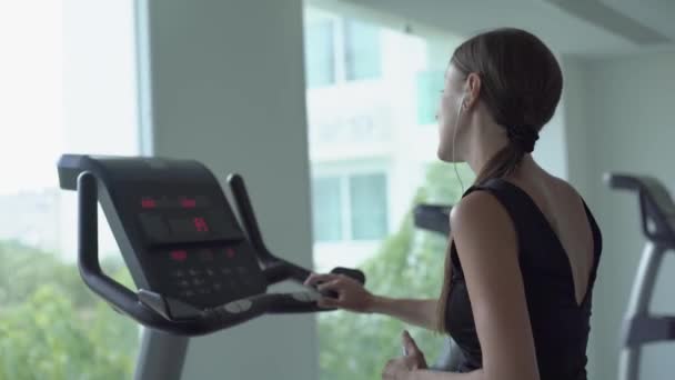Exercício de bicicleta cardio treino no ginásio de fitness da mulher tomando perda de peso. A fêmea ouve música nos auscultadores. Atleta construtor músculos estilo de vida . — Vídeo de Stock