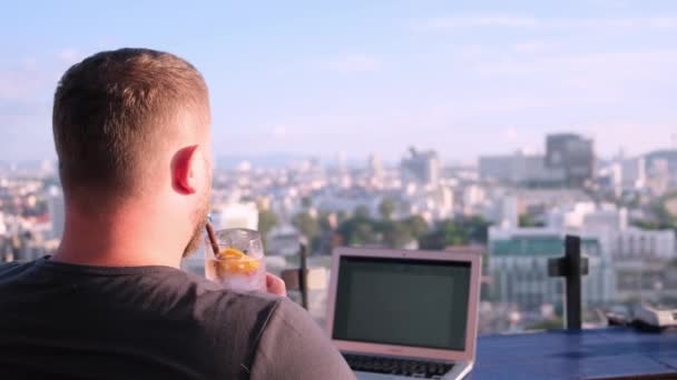 Pattaya, Tayland - 15 Mayıs 2019: güzel panoramik manzaralı çatıda bir kafede dizüstü bilgisayar üzerinde çalışan erkek. adam bir kokteyl içme ve bir bilgisayar üzerinde çalışan. — Stok video