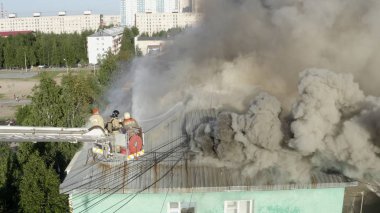 Nizhnevartovsk, Rusya - 1 Temmuz 2019: İtfaiyeciler bir konut yüksek binanın çatısında bir yangın söndürmek. üst görünüm
