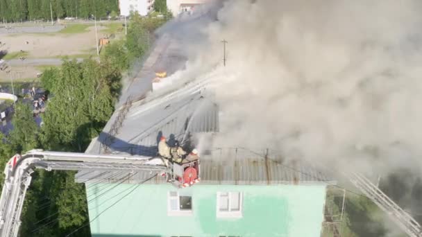 Nizhnevartovsk, Rusia - 1 de julio de 2019: los bomberos apagan un incendio en el techo de un edificio residencial de gran altura. vista superior — Vídeos de Stock