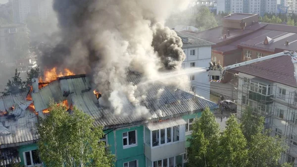 İtfaiyeciler bir konut yüksek binanın çatısında bir yangın söndürmek. üst görünüm