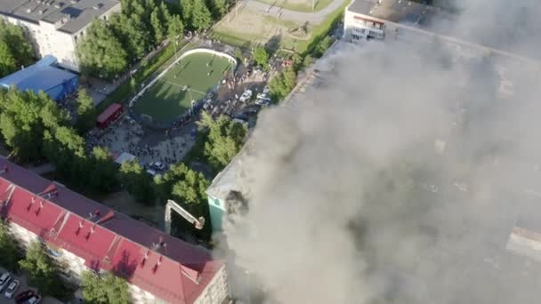Nizhnevartovsk, Rusia - 1 de julio de 2019: los bomberos apagan un incendio en el techo de un edificio residencial de gran altura. vista superior — Vídeo de stock