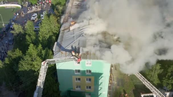 Nizhnevartovsk, Rusia - 1 de julio de 2019: los bomberos apagan un incendio en el techo de un edificio residencial de gran altura. vista superior — Vídeos de Stock