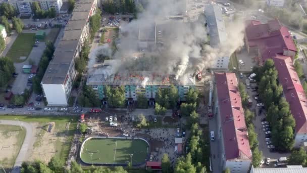 Nizhnevartovsk, Rusia - 1 de julio de 2019: los bomberos apagan un incendio en el techo de un edificio residencial de gran altura. vista superior — Vídeos de Stock