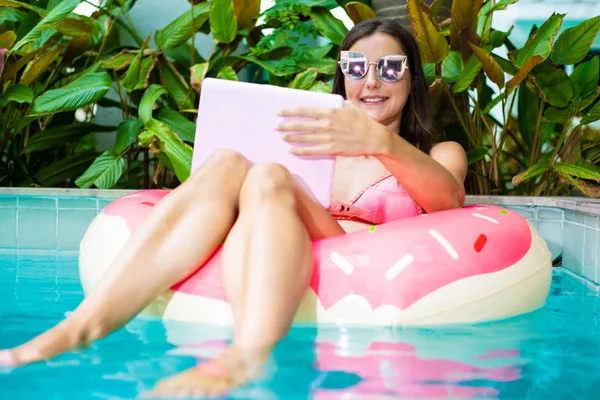 Молода фрілансерка сидить з ноутбуком у надувному колі в басейні. Зайнятий під час канікул. Віддалена концепція роботи. вибірковий фокус — стокове фото