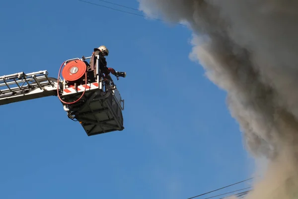 I pompieri sulle scale spengono un incendio sul tetto di un grattacielo residenziale. vista dall'alto — Foto Stock