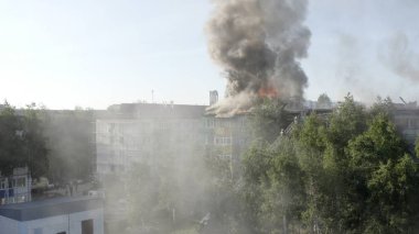 Yüksek katlı bir binanın yanan çatısı, yangından duman bulutları. üst görünüm