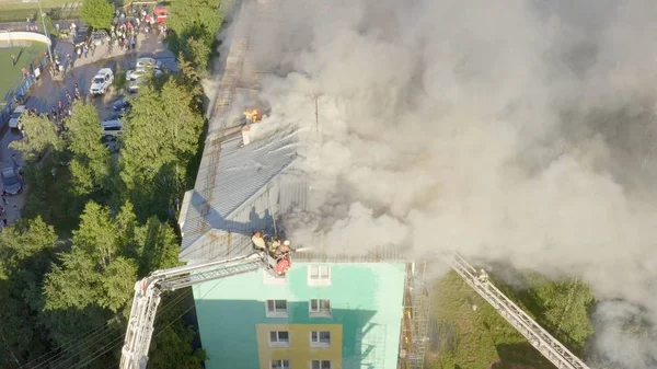 Burning roof of a residential high-rise building, clouds of smoke from the fire. firefighters extinguish the fire. top view