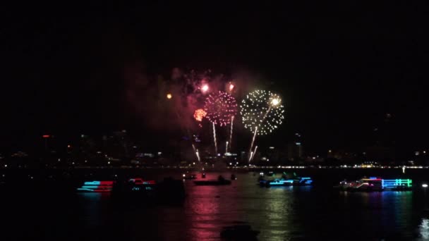 Fuegos artificiales sobre paisaje urbano junto a la playa y el mar que rodea con hoteles, restaurantes y barcos de servicio y cruceros durante el crepúsculo azul para celebrar la víspera de Año Nuevo y la ocasión especial en . — Vídeo de stock