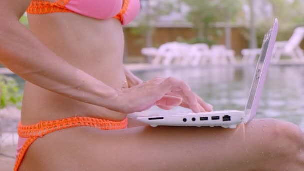 Jovem freelancer feminino sentado com laptop perto da piscina. Ocupado durante as férias. O conceito de trabalho remoto. close-up — Vídeo de Stock