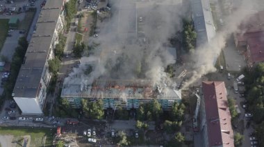 Yüksek katlı bir binanın yanan çatısı, yangından duman bulutları. üst görünüm
