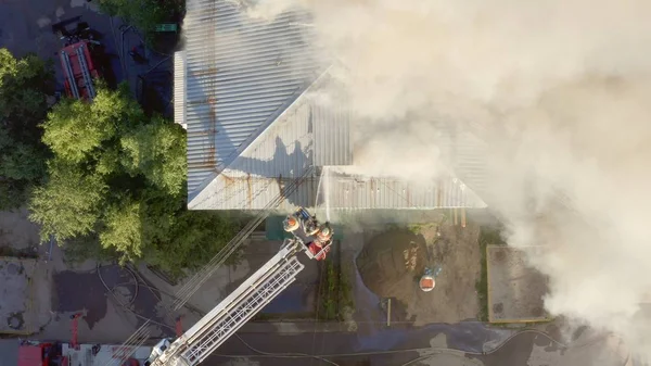 Burning roof of a residential high-rise building, clouds of smoke from the fire. firefighters extinguish the fire. top view