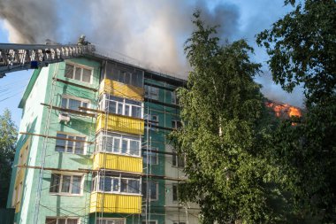 Yüksek katlı bir binanın yanan çatısı, yangından duman bulutları. üst görünüm