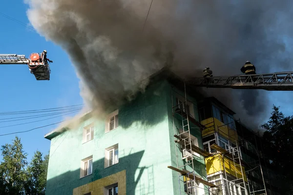 I pompieri sulle scale spengono un incendio sul tetto di un grattacielo residenziale. vista dall'alto — Foto Stock