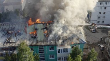 Yüksek katlı bir binanın yanan çatısı, yangından duman bulutları. üst görünüm