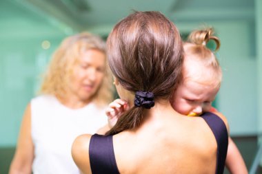 Sad little girl on hands at mum. Woman swears at mom with baby. clipart