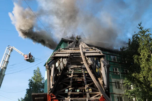 I pompieri sulle scale spengono un incendio sul tetto di un grattacielo residenziale. vista dall'alto — Foto Stock