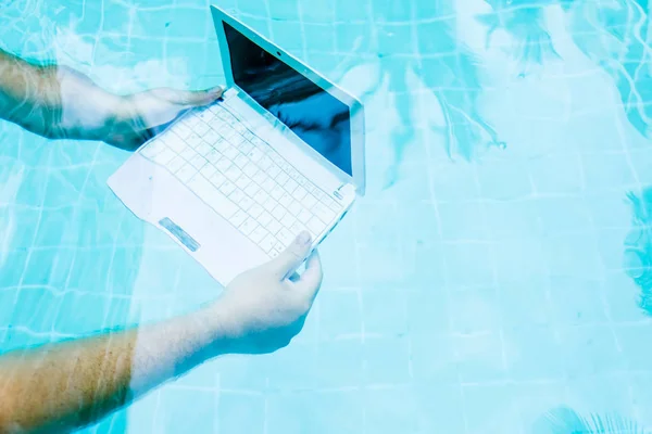 Чоловічі руки з ноутбуком, що працює під водою. Поняття перешкод у роботі. Розмитий абстрактний фон . — стокове фото