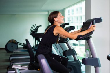 Kilo kaybı alarak kadının fitness salonunda egzersiz bisiklet kardiyo egzersiz. kadın kulaklıkla müzik dinler. Atlet oluşturucu kasları yaşam tarzı.