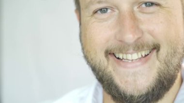 Beyaz bir arka plan üzerinde gülümseyen sakallı yakışıklı Beyaz adam, yarım yüz bir adam portresi.