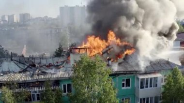 Yüksek katlı bir binanın yanan çatısı, yangından duman bulutları. üst görünüm