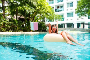 kadın serbest havuzda şişme bir daire içinde oturur ve suya dizüstü atar. Tatillerde meşgul. Uzaktan çalışma kavramı. seçici odaklama