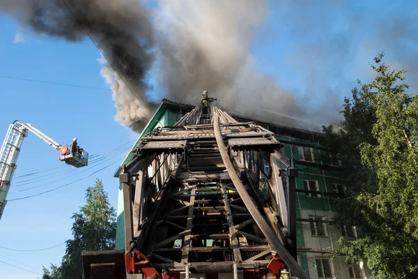 Les pompiers dans les escaliers éteignent un incendie sur le toit d'un immeuble résidentiel de grande hauteur. vue de dessus — Photo