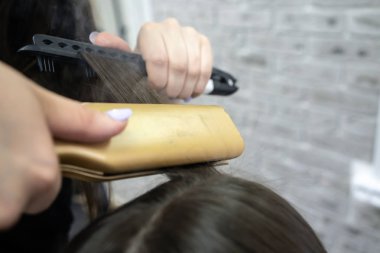 Uzun esmer saç Kuaför ile sevimli kız bir güzellik salonunda saç laminasyon yapıyor. saç bakım tedavisi kavramı