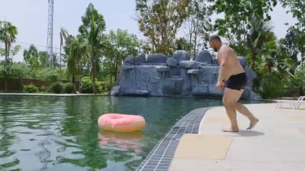 Uomo divertente salta in un cerchio gonfiabile rosa in una piscina. tempo libero, concetto di partito . — Video Stock