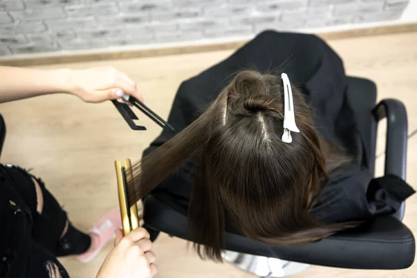Menina bonito com cabelos longos morena cabeleireiro fazendo laminação de cabelo em um salão de beleza. conceito de tratamento de cabelo, vista superior — Fotografia de Stock