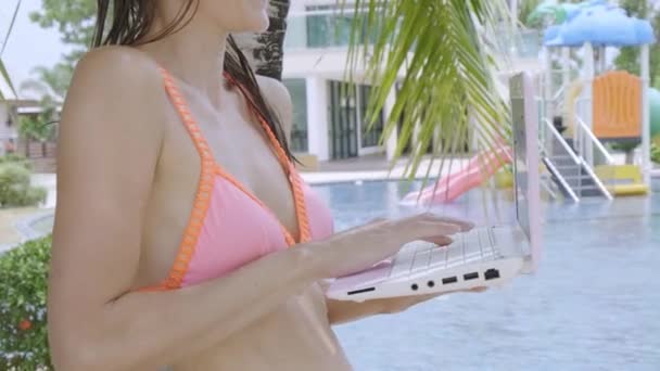 Joven freelancer sentada con laptop cerca de la piscina. Ocupado durante las vacaciones. El concepto de trabajo remoto. primer plano — Vídeo de stock