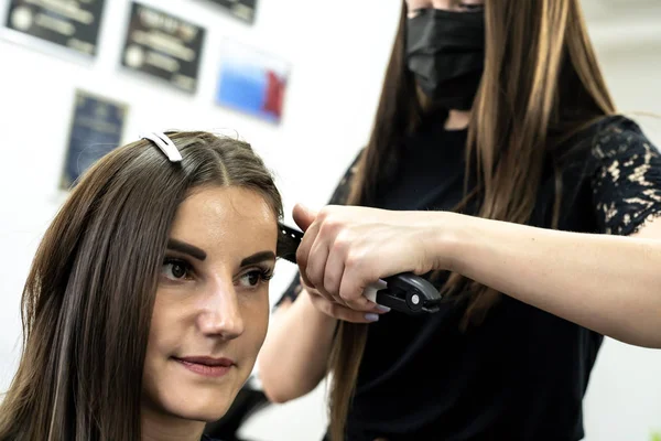Coiffeur fait stratification des cheveux dans un salon de beauté pour une fille aux cheveux bruns. concept de soins capillaires . — Photo