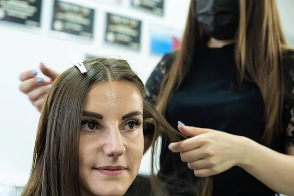 Coiffeur fait stratification des cheveux dans un salon de beauté pour une fille aux cheveux bruns. concept de soins capillaires . — Photo